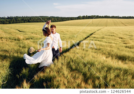 In dress and formal clothes. Couple just married. Together on the majestic agricultural field at sunny day 124626544