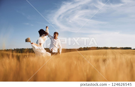 In dress and formal clothes. Couple just married. Together on the majestic agricultural field at sunny day 124626545