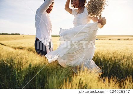 In dress and formal clothes. Couple just married. Together on the majestic agricultural field at sunny day In dress and formal clothes. Couple just married. Together on the majestic agricultural field at sunny day 124626547