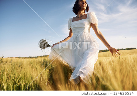 Beautiful young bride in white dress is on the agricultural field at sunny day Beautiful young bride in white dress is on the agricultural field at sunny day 124626554
