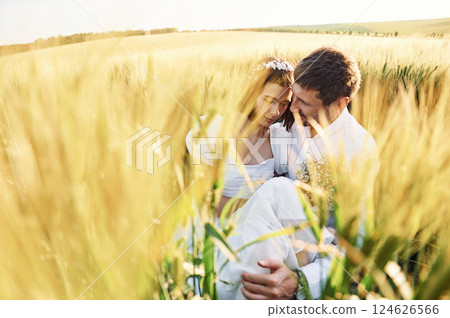 Sitting in the wheat. Happy people. Couple just married. Together on the majestic agricultural field at sunny day 124626566