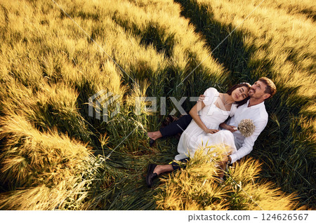 Sitting on the ground. Couple just married. Together on the majestic agricultural field at sunny day 124626567