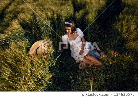 Top view. Beautiful young bride in white dress is on the agricultural field at sunny day 124626573