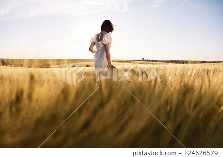 Enjoying the nature. Beautiful young bride in white dress is on the agricultural field at sunny day 124626579