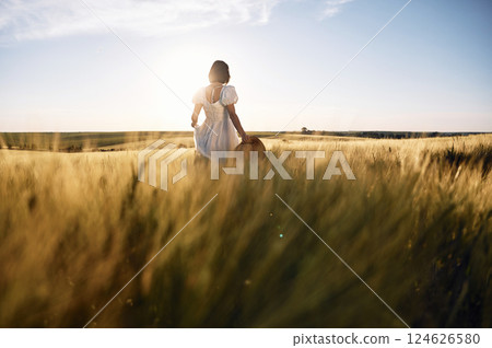 Enjoying the nature. Beautiful young bride in white dress is on the agricultural field at sunny day 124626580