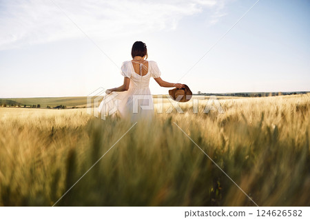 Enjoying the nature. Beautiful young bride in white dress is on the agricultural field at sunny day 124626582