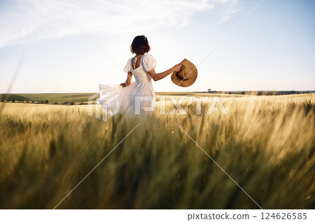 Majestic view. Beautiful young bride in white dress is on the agricultural field at sunny day 124626585