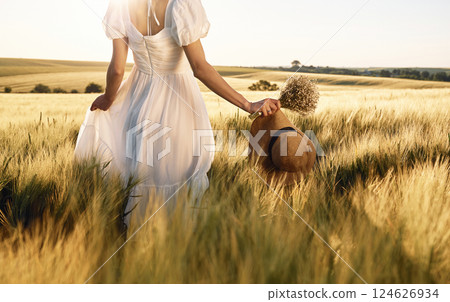 Cropped view. Holding hat in hand. Beautiful young bride in white dress is on the agricultural field at sunny day 124626934
