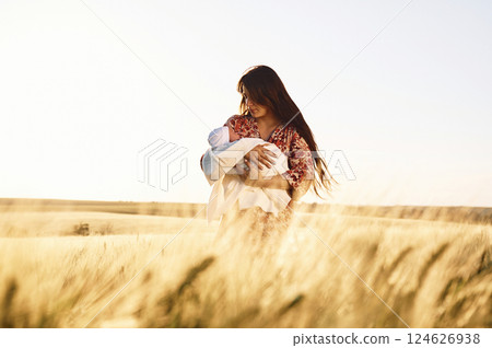Front view. Gorgeous woman is on the agricultural field with her newborn baby 124626938
