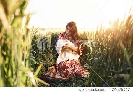 Conception of parenting. Gorgeous woman is on the agricultural field with her newborn baby 124626947
