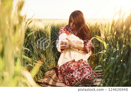Conception of parenting. Gorgeous woman is on the agricultural field with her newborn baby 124626948