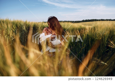 Conception of parenting. Gorgeous woman is on the agricultural field with her newborn baby 124626949