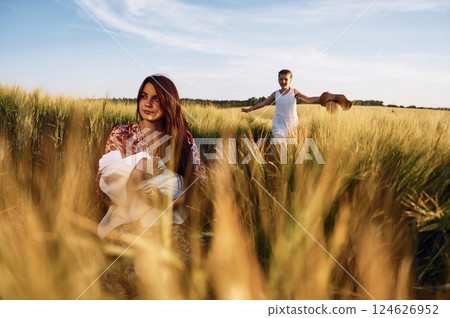Woman is sitting on the ground. Mother with her newborn baby and girl is on the field at sunny day together Woman is sitting on the ground. Mother with her newborn baby and girl is on the field at sunny day together 124626952