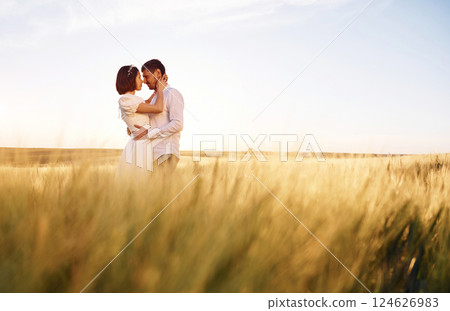 Standing and embracing. Couple just married. Together on the majestic agricultural field at sunny day Standing and embracing. Couple just married. Together on the majestic agricultural field at sunny day 124626983