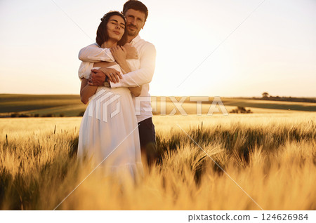 Standing and embracing. Couple just married. Together on the majestic agricultural field at sunny day 124626984
