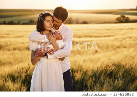 Front view. Embracing each other. Couple just married. Together on the majestic agricultural field at sunny day 124626988