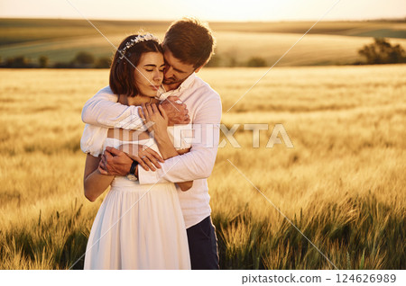 Front view. Embracing each other. Couple just married. Together on the majestic agricultural field at sunny day 124626989