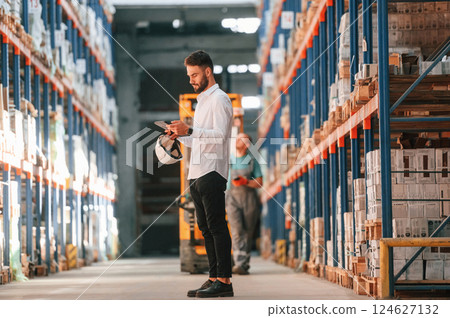 Using tablet to check the products. Storage worker is in the warehouse Using tablet to check the products. Storage worker is in the warehouse 124627132