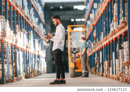 Using tablet to check the products. Storage worker is in the warehouse Using tablet to check the products. Storage worker is in the warehouse 124627133