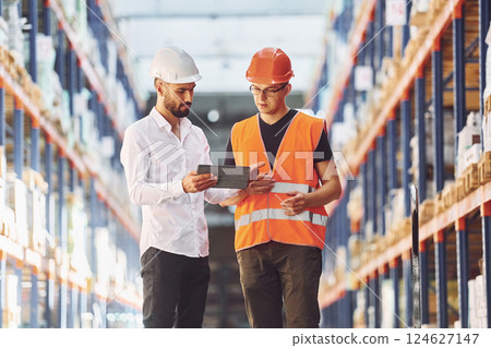 Standing and working together. Two men in storage is in the warehouse Standing and working together. Two men in storage is in the warehouse 124627147