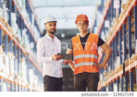 Standing and working together. Two men in storage is in the warehouse Standing and working together. Two men in storage is in the warehouse 124627148