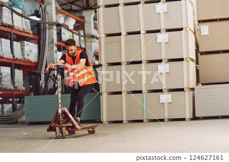 Riding the platform trolley. Storage worker is in the warehouse with bunch of products Riding the platform trolley. Storage worker is in the warehouse with bunch of products 124627161