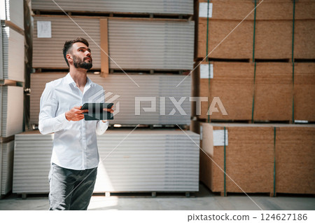 In formal clothes. Storage worker is in the warehouse with bunch of products 124627186