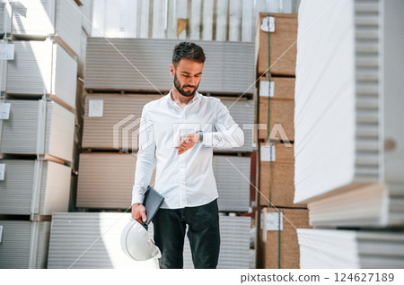 In formal clothes. Storage worker is in the warehouse with bunch of products In formal clothes. Storage worker is in the warehouse with bunch of products 124627189