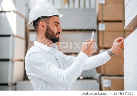 In white hard hat. Storage worker is in the warehouse with bunch of products 124627195