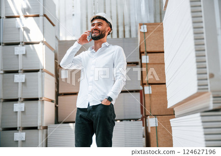 Using phone. Storage worker is in the warehouse with bunch of products 124627196