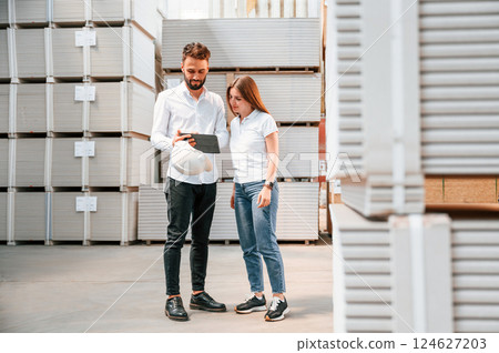 Young manager in formal clothes is working with woman in the warehouse Young manager in formal clothes is working with woman in the warehouse 124627203