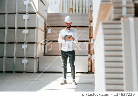 Serious manager in formal clothes. Storage worker is in the warehouse with bunch of products Serious manager in formal clothes. Storage worker is in the warehouse with bunch of products 124627229