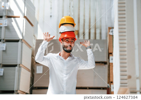 Having fun with hard hats. Storage worker is in the warehouse with bunch of products 124627384