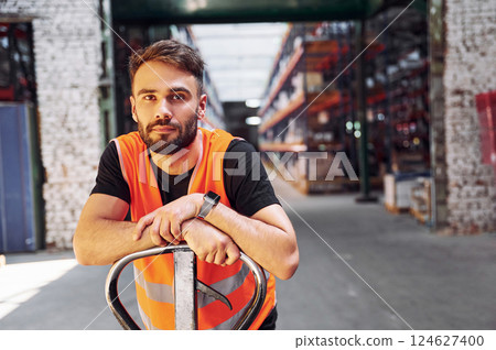 Trolley platform. Storage worker is in the warehouse with bunch of products 124627400
