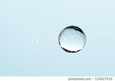 Collagen drop on blue background with copy space. Abstract blue liquid droplet for design. Hyaluronic acid gel swatch, anti aging , moisturising skin care. 124627420