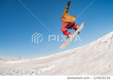 Snowboarder jumping against blue sky Snowboarder jumping against blue sky 124628126
