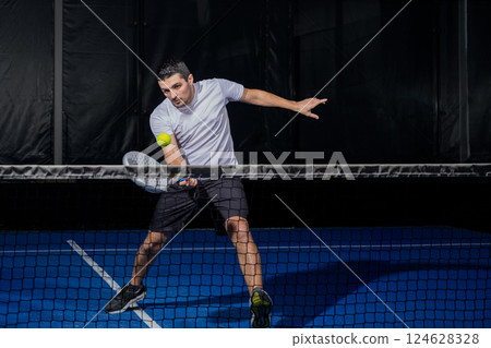 Padel player hitting ball with a racket 124628328