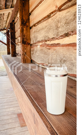 beige thermos mug in hand during walk in park 124628913
