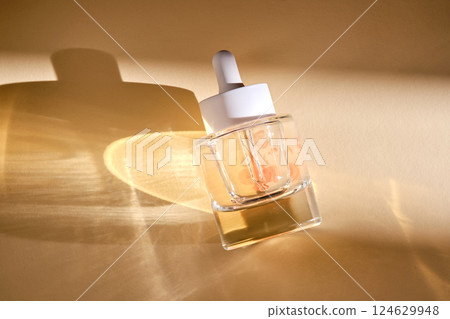 A bottle of luxury serum with petals on a beige background. A bottle of luxury serum with petals on a beige background. 124629948