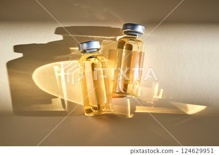 Injection vials with medicinal product in sunlight on beige background. Injection vials with medicinal product in sunlight on beige background. 124629951
