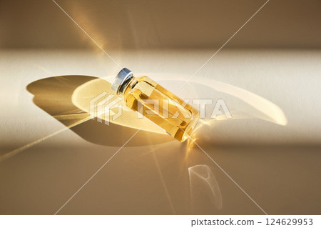 Injection vial with medicinal product in sunlight on beige background. 124629953