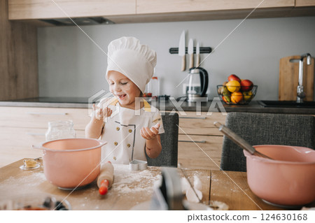 Happy little chef, flour, knead the dough. The cook girl blows on the flour. Home cooking. kitchen Happy little chef, flour, knead the dough. The cook girl blows on the flour. Home cooking. kitchen 124630168