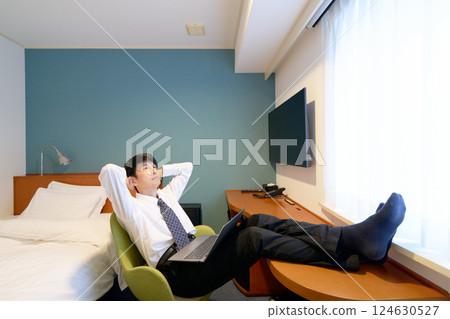 一位商人在出差期間，將雙腳擱在飯店的桌子上休息 124630527