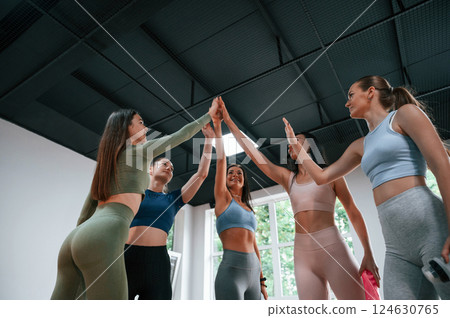 Conception of success. Giving high fives. Group of women practicing fitness in the gym Conception of success. Giving high fives. Group of women practicing fitness in the gym 124630765