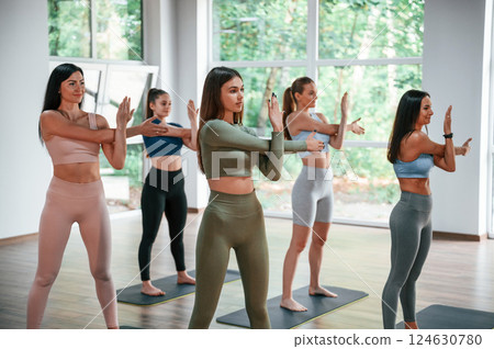 Standing and doing warm up exercises. Group of women practicing fitness in the gym 124630780
