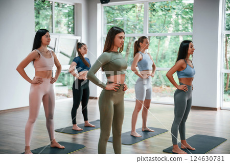 Standing and doing warm up exercises. Group of women practicing fitness in the gym 124630781