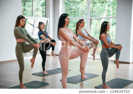 Standing and doing warm up exercises. Group of women practicing fitness in the gym 124630783