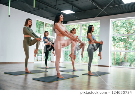 Standing and doing warm up exercises. Group of women practicing fitness in the gym 124630784