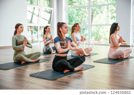 Sitting in lotus pose. Group of women practicing fitness in the gym 124630802