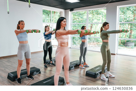 Slim body types. Doing exercises. Group of women practicing fitness in the gym Slim body types. Doing exercises. Group of women practicing fitness in the gym 124630836